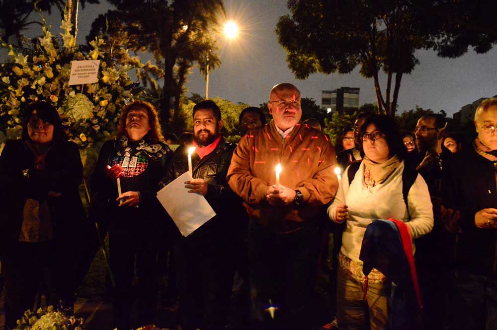 Personas sosteniendo velas en memoria de una persona LGBT asesinada