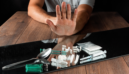 A hand rejecting cocaine in various versions, including powder, syringe, etc.