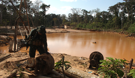 Un soldado revisa dos estructuras de madera que flotan en aguas estancadas