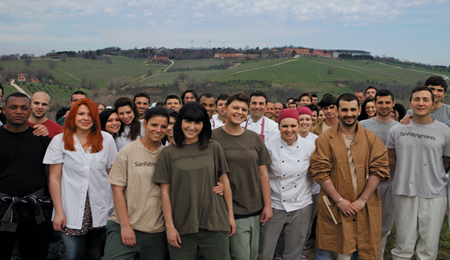 Group picture of people at the San Patrignano headquarters involved in their socio-occupational program. They are wearing shorts with the San Patrignano logo. 