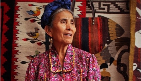 Mujer indígena mayor tejiendo una manta  