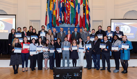 32 people show their certificate, standing with the flags of the OAS Member States behind them. Diploma in Governance, Management and Public Leadership in the Inter-American System